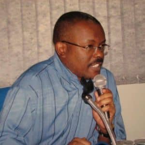 osé Carlos do Nascimento discursando com um microfone em uma palestra sindical sobre as leis e garantias de direitos para trabalhadores domésticos.